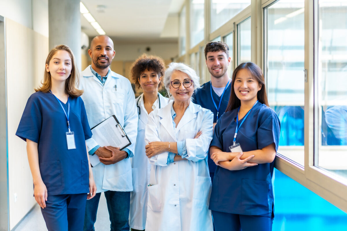 A diverse group of healthcare professionals, including a chiropractor and a surgeon, collaborating in a modern hospital hallway.