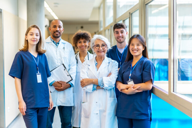 A diverse group of healthcare professionals, including a chiropractor and a surgeon, collaborating in a modern hospital hallway.