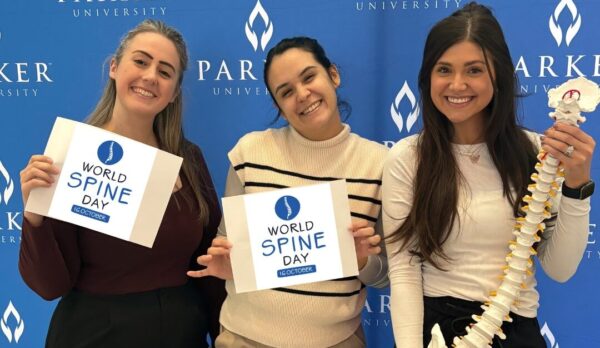 This image shows three individuals standing together in front of a blue backdrop with the Parker University logo