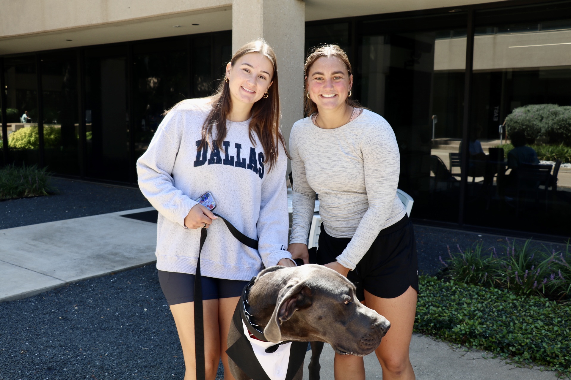 Two Parker students smile while posing with Parker, Parker University's security dog (a great dane)