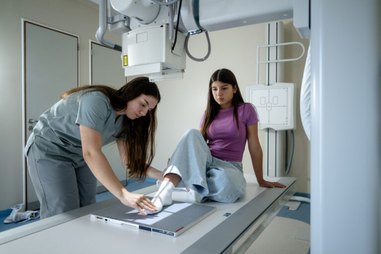 Rad tech in green scrubs positions a patient's foot for an x-ray